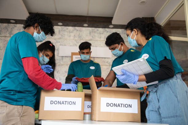 Dayitwa NGO activities showing health workers in protective suits distributing food and supplies to children wearing masks during the COVID-19 relief effort.